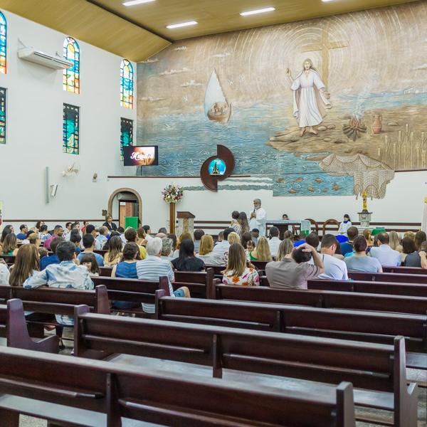 Fiéis reunidos durante a missa, com o painel em relevo ao fundo