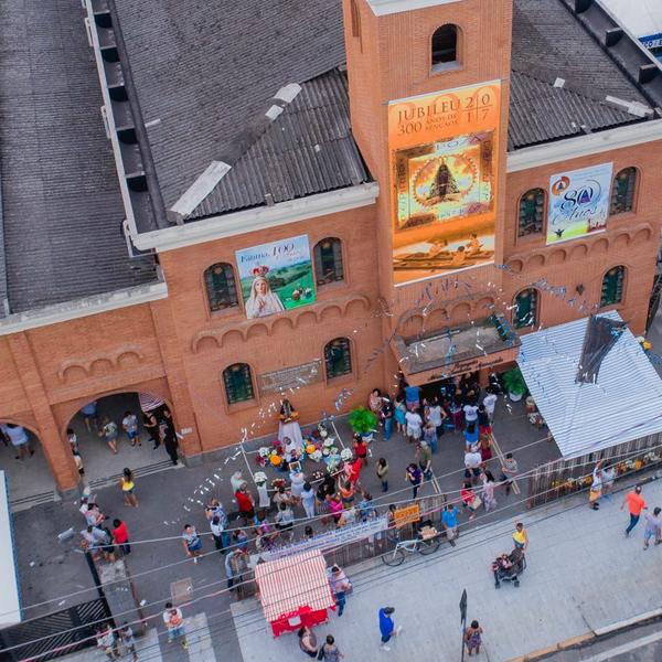 Vista aérea da festa na frente da igreja, com a rua cheia de fiéis